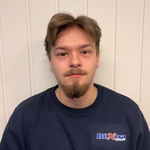 Mann i blå genser foran hvit trevegg